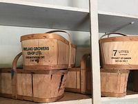 Group of vintage wood apple baskets with markings from Vineland Growers Co-op Ltd. and capacity information.