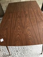 Top-down view of the rectangular walnut veneer table top with visible wood grain and extension insert in the middle.