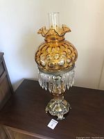 Full view of vintage hurricane lamp with amber hobnail glass globe, clear glass chimney, and dangling prisms.