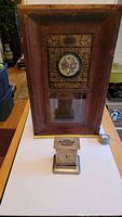 Full view of both items: the 1860s wooden clock case with decorative glass panel and the small brass carriage clock in front