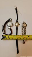Full lot view of three ladies wristwatches with measuring tape showing size