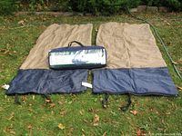 Two sleeping bags laid flat on grass with the tent in its bag on top, showing condition and size.
