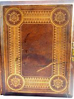 Top view of the Bible cover showing elaborate gold embossed decoration and leather texture with some wear and scratches.