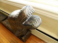 Close up of the carved animal head at one end of the bench showing detailed teeth and chain pattern.