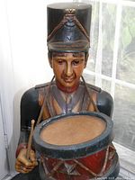 Close-up frontal view of torso and drum, carved facial and paint detail