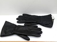 Pair of black leather gloves laid flat with palm side down showing full length and gauntlet cuffs.