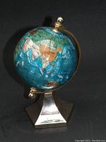 Turquoise gemstone inlay world globe on metallic zinc alloy stand, showing detailed landmasses and gemstone inserts