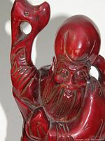 Close-up photo of the statue showing detailed carving of the head, face, beard and arm holding the staff