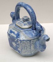 Side angled view of the blue-white porcelain octagonal teapot showing the dragon spout, octagonal body, and handle detail.