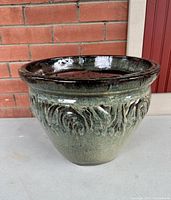 Front angled photo of the terracotta planter showcasing green growth textured glaze and rounded shape.