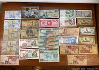 Top-down view of the entire collection showing paper money and a box of coins on a wooden table.