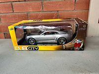 Front-side view of the unopened 2006 silver Chevy Camaro Concept diecast car in yellow and black Dub City box showing clear display window.