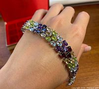 Bracelet worn on wrist showing vibrant multicolored gemstones in silver setting.