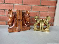 Full view of hand carved wood horse head bookends and brass horse bookends side by side on a brick surface.