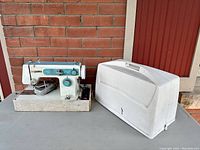 Photo showing vintage Morse zig zag sewing machine with foot pedal and carrying case on ground with brick wall background.