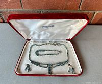 Full view of the demi parure inside a vintage red velvet case with white satin lining and 'Eisenstadt' branding, showing necklace, bracelet, and earrings.