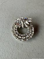 Front view of the vintage Sherman rhinestone brooch showing clear rhinestones in asymmetrical circular design.