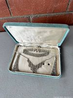 Photo of the open jewelry box showing the full vintage sterling silver demi parure set consisting of earrings, necklace, and bracelet laid inside the lined case.