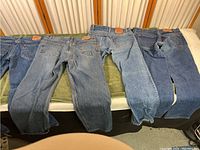 Four pairs of Levi's jeans laid flat on a surface showcasing the full length and color of denim.