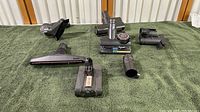 Full overview of all Dyson vacuum accessories on green fabric background including brush heads, connectors, and battery