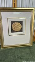 Framed artwork showing the Greek Tetradrachm Owl of Athena coin relief with gold-tone on dark and white linen mat.