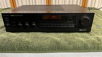 Full front and top view of the black Sherwood stereo receiver on a green towel background showing power and control buttons, model number on the top left.