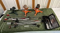 Lot contents showing two adjustable shooting rests and multiple cleaning rods with various attachments laid out on cloth surface.