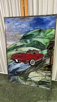 Full view of the double sided stained glass artwork showing a red sports car on a road with green hills and a blue sky.