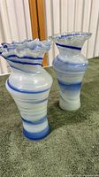 Pair of vintage Becraft glass vases with blue and white swirled pattern and clear ruffled edges on a towel surface, side view.
