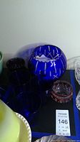 Photo showing large blue spherical cut to clear bowl alongside blue glasses