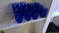 12 Hazel Atlas blue glass tumblers displayed on shelving; 6 large and 6 small pieces, each with vertical fine ribbed pattern, cobalt blue in color