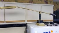 Full view of the long arm brass desk lamp with marble and brass base on a white surface.
