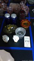 Photo showing blue salt and pepper shakers, amber glass dish with cat figurine, white owl salt and pepper shakers, and several other glassware items.