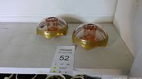 Two pink Depression glass candle holders with rolled rims and gold floral pattern on a white surface.