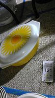 Photo of a white Pyrex casserole dish with yellow sunflower lid, showing condition and design.