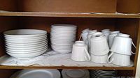 Shelves with stacks of plates, bowls, cups, and saucers