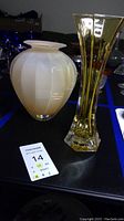 Pair of vases on a table, white frosted round vase next to tall amber colored vase