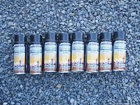 Photo showing all 8 cans of Mercury Storage Seal spray aligned in a row on a rough surface.