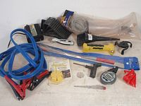 Full lot overview showing assorted automotive car care tools and accessories including jumper cables, various hand tools, measuring devices and accessories