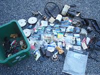 Overview photo of a green box filled with assorted boat parts including seals, wiring, hoses, circular metal and plastic components, and a black steering wheel.