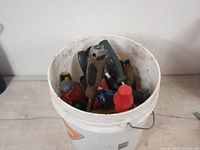 Bucket containing mixed screwdrivers of various brands and handle colors, showing wear and use.