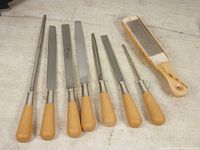 Full set of eight Lee Valley woodworking files and brush displayed on a light surface showing wooden handles and metal blades or bristles.