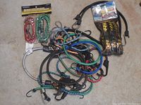 Photo showing a variety of bungee cords and tie downs spread out on a surface, some still in packaging.