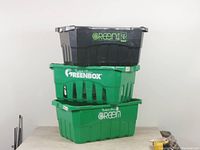 Stacked view of three hard plastic grocery storage bins of two colors and different sizes with visible branding.