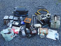 Overview of all vintage boat parts including cover, fuel tank, pumps, wiring, manuals, and small parts in boxes and bags.