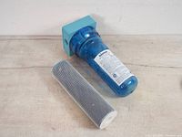 Rainfresh FC200 whole house water filter displayed with cylindrical mesh cartridge separated from filter housing on a light surface