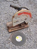 Skil Saw Professional 14-inch chop saw on gravel surface with a replacement abrasive blade in front.