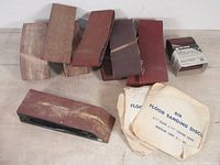 Lot of sanding belts, sanding discs in packaging, and a sanding block