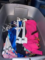 Photo showing multiple bikinis on white hangers inside a gray plastic bin.