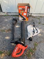 Full view of Black & Decker leaf blower, two detachable nozzles, white fabric collection bag, and original box.